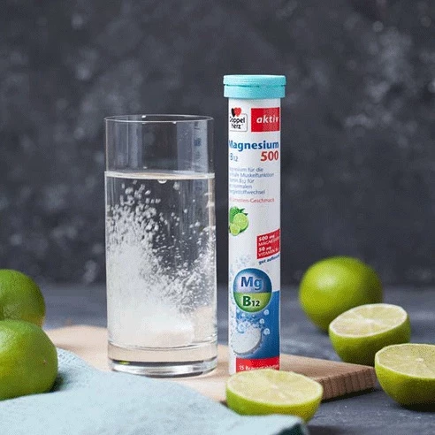 Doppelherz Magnesium 500 + B12 neben Limetten und Glas mit Brausetablette